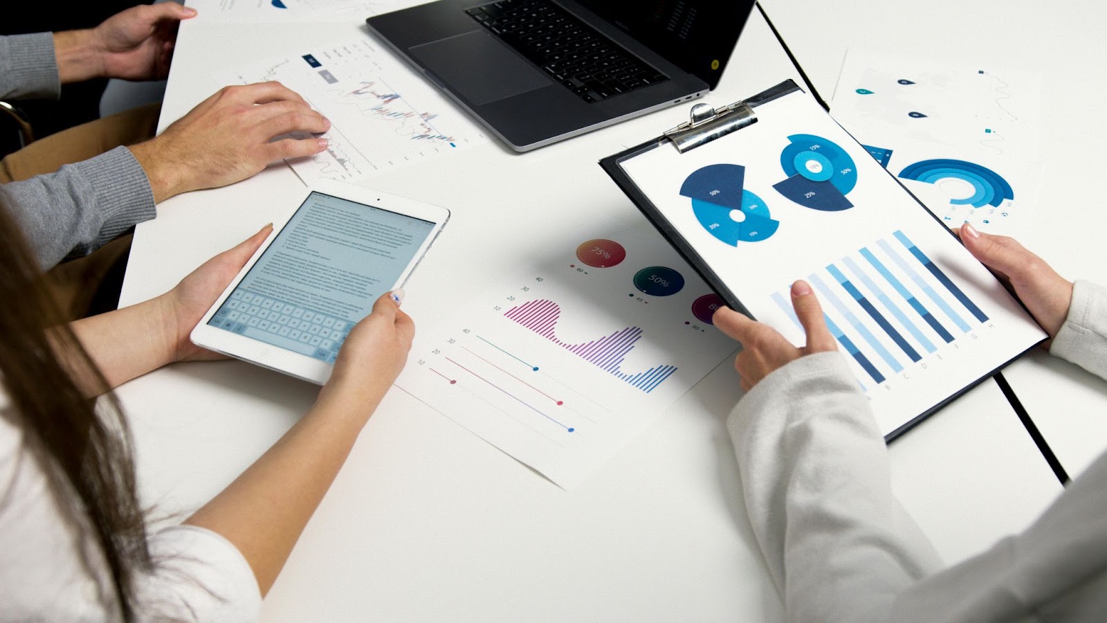 Three people sitting around a table looking at graphs and charts. 