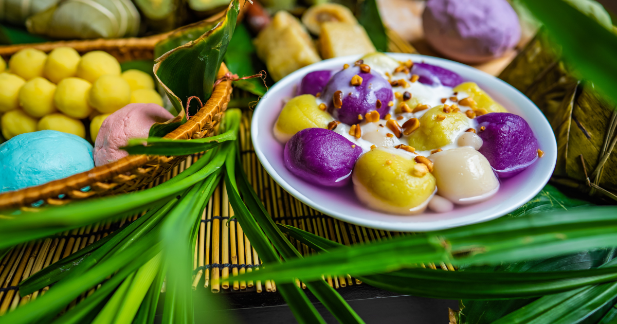 Colourful Vietnamese dessert with purple, yellow, and white sticky rice balls in coconut milk, topped with roasted peanuts