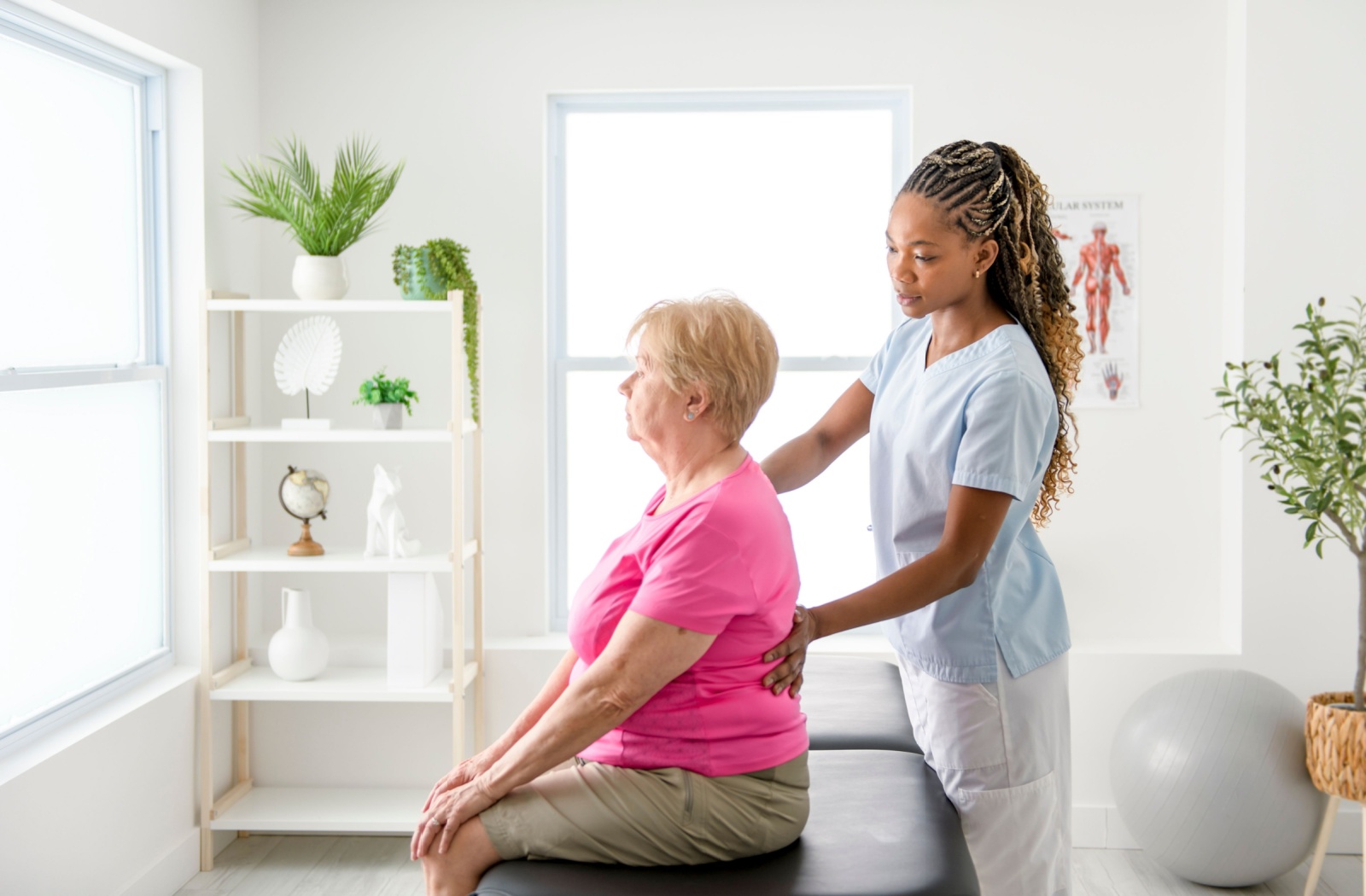 A physiotherapist helping a senior woman perform an exercise while supporting her back