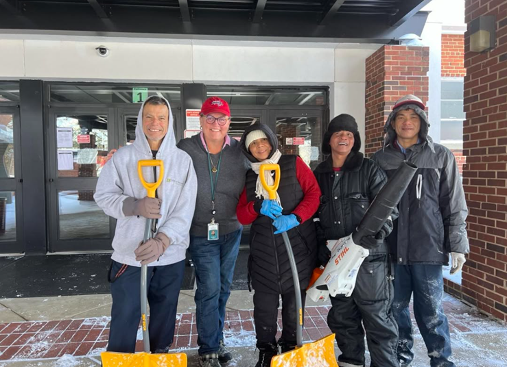 Dr. Reid with custodians at Luther Jackson Middle School holding snow shovels.