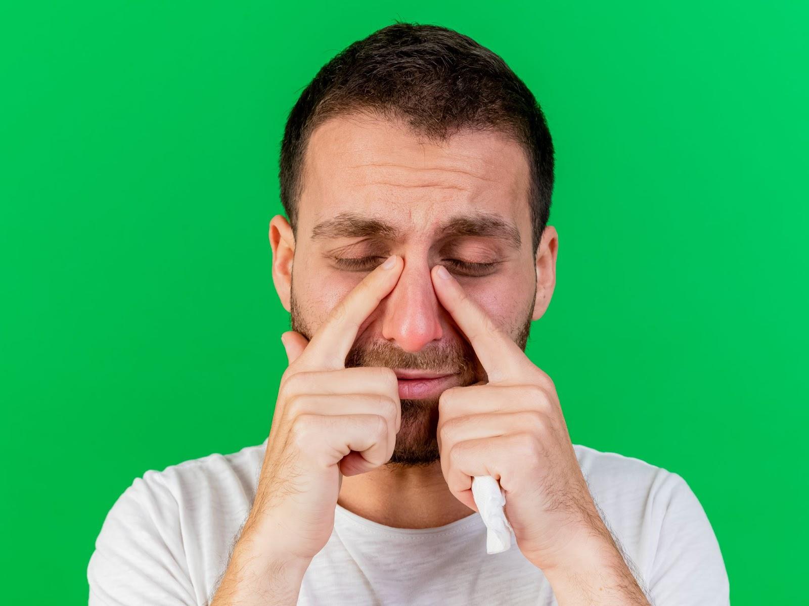 A person with his hands on his nose

Description automatically generated