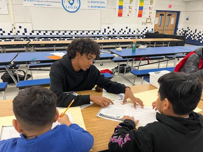 High school student working with elementary age students at Braddock Elementary School. 