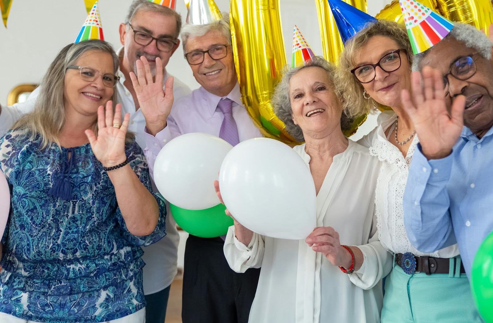 People wearing party hats and holding balloons | Source: Pexels