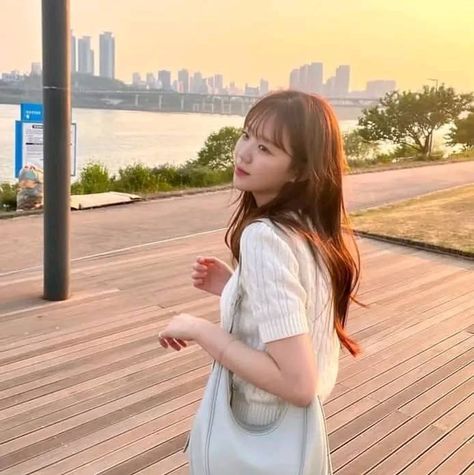 This contain Ji Ye Eun  is standing on a boardwalk with her hand in her pocket and looking up at the sky