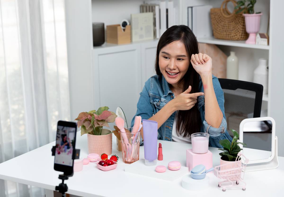 Asian beauty content creator filming a product review and swatch demo at home