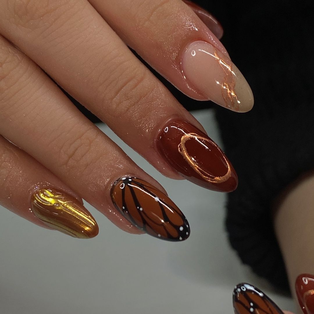 Close-up of hand with glossy, multicolored manicured nails, some adorned with butterfly wing designs.