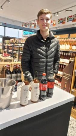 A person standing in front of a counter with bottles of liquor

Description automatically generated