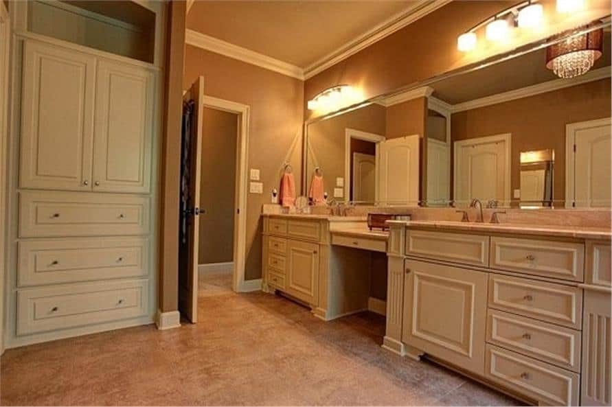 Primary bathroom with a tall cabinet and a dual sink vanity paired with a frameless mirror.