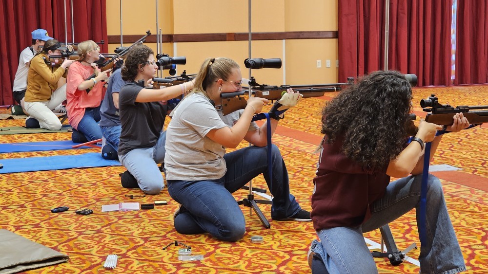 Line of contestants in the kneeling position take their shot at victory.