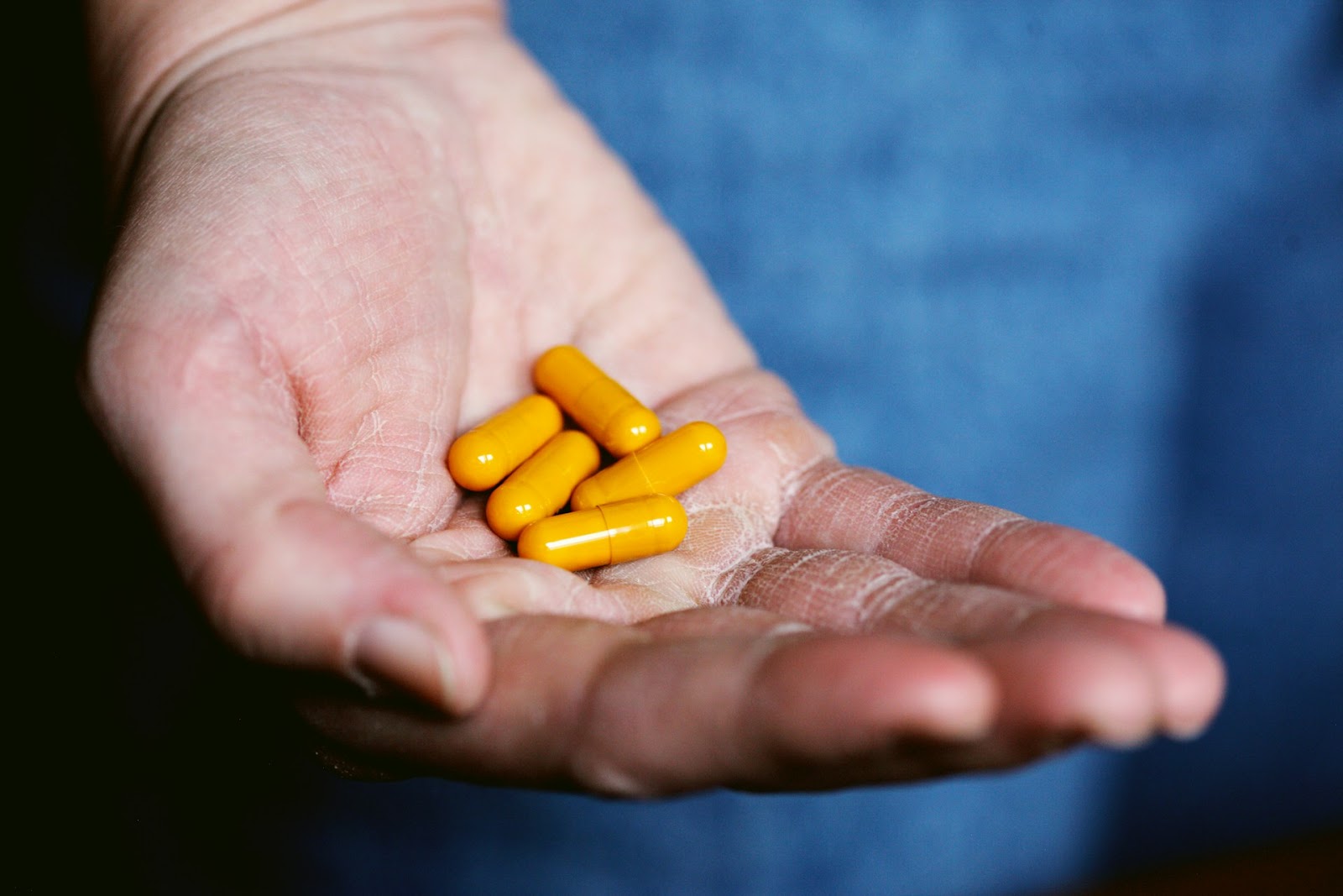 A hand with five yellow pills