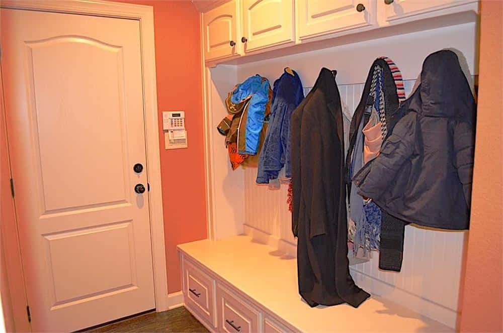 Mudroom with white storage cabinets, coat hooks, and a built-in bench.