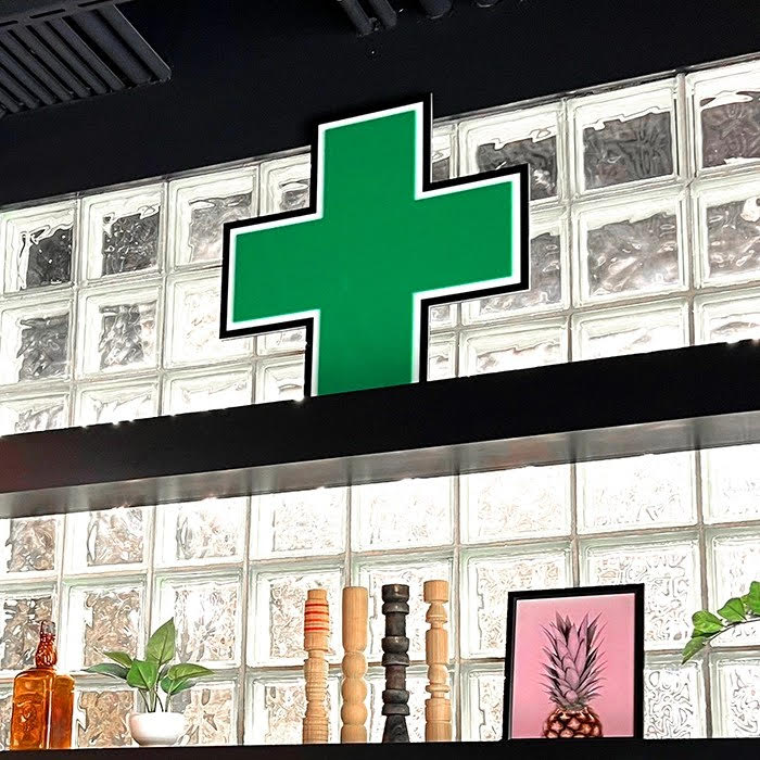 a LED green cross sign on a shelf at a dispensary as an example of the power of LED signage