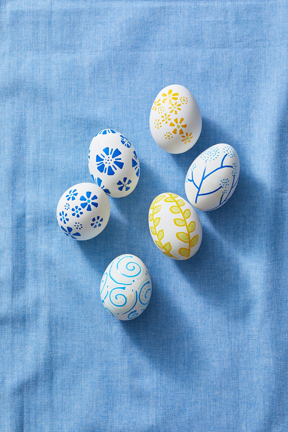 easter egg hunt ideas, white eggs decorated with swirls, branches and flowers