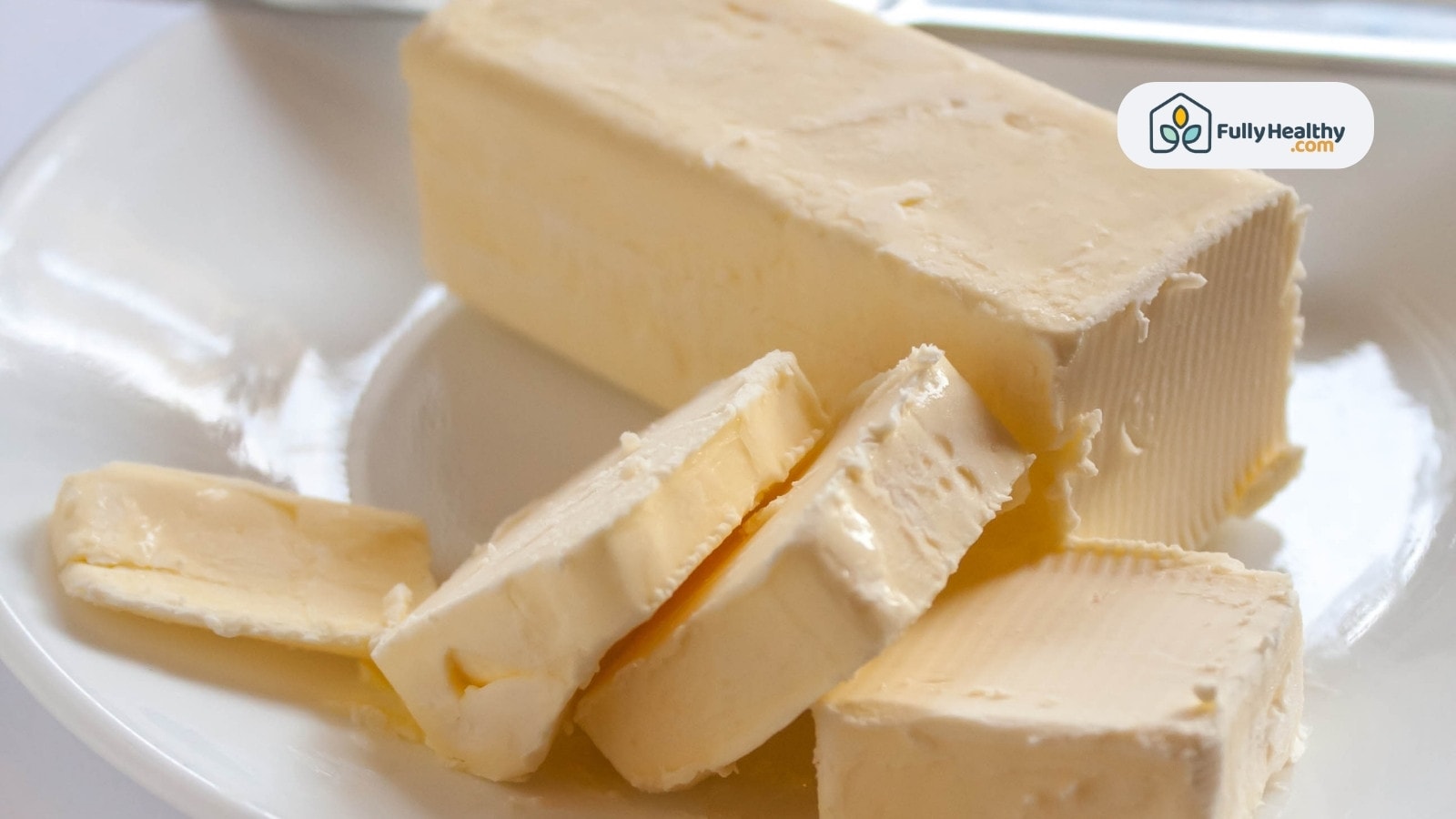 Sliced creamy butter on white plate in soft lighting