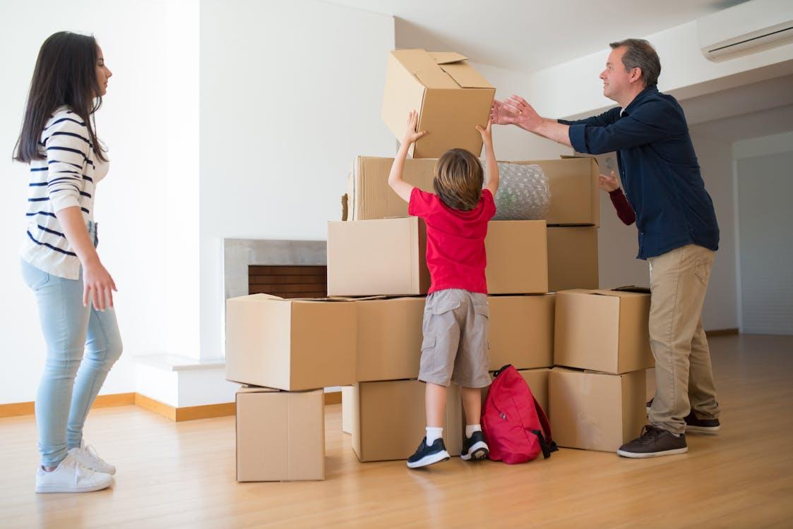 Free A family working together to move cardboard boxes inside their new home. Stock Photo