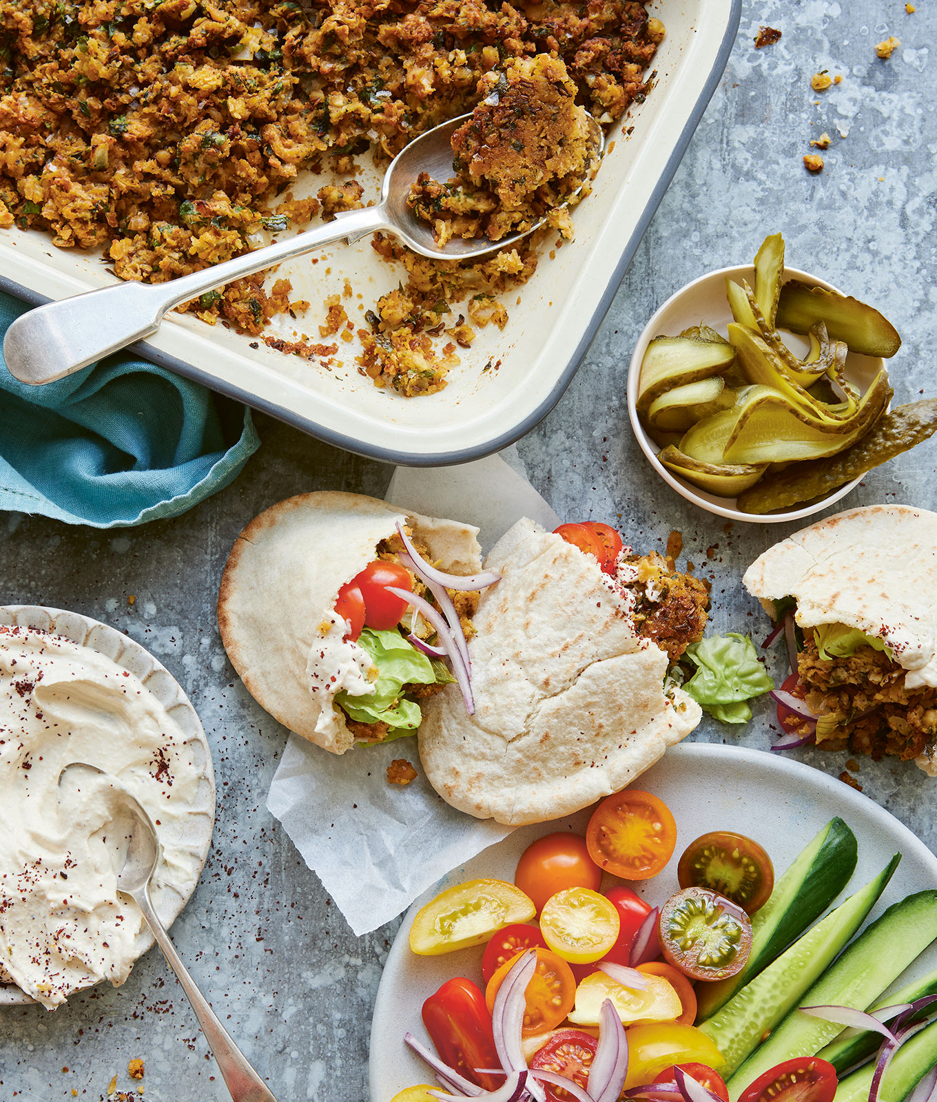 passover recipes: sheet pan falafel on a counter next to pita, crudite and yogurt tahini sauce