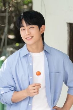  A  photo of Jung Hae In on a sky blue shirt and a polo inside of it and holding a sweet