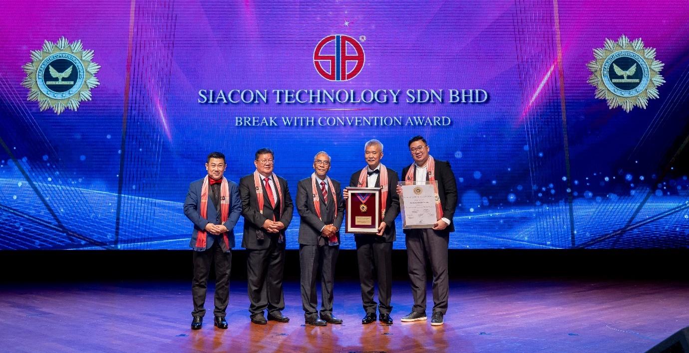 A group of men standing on a stage holding a plaque

Description automatically generated