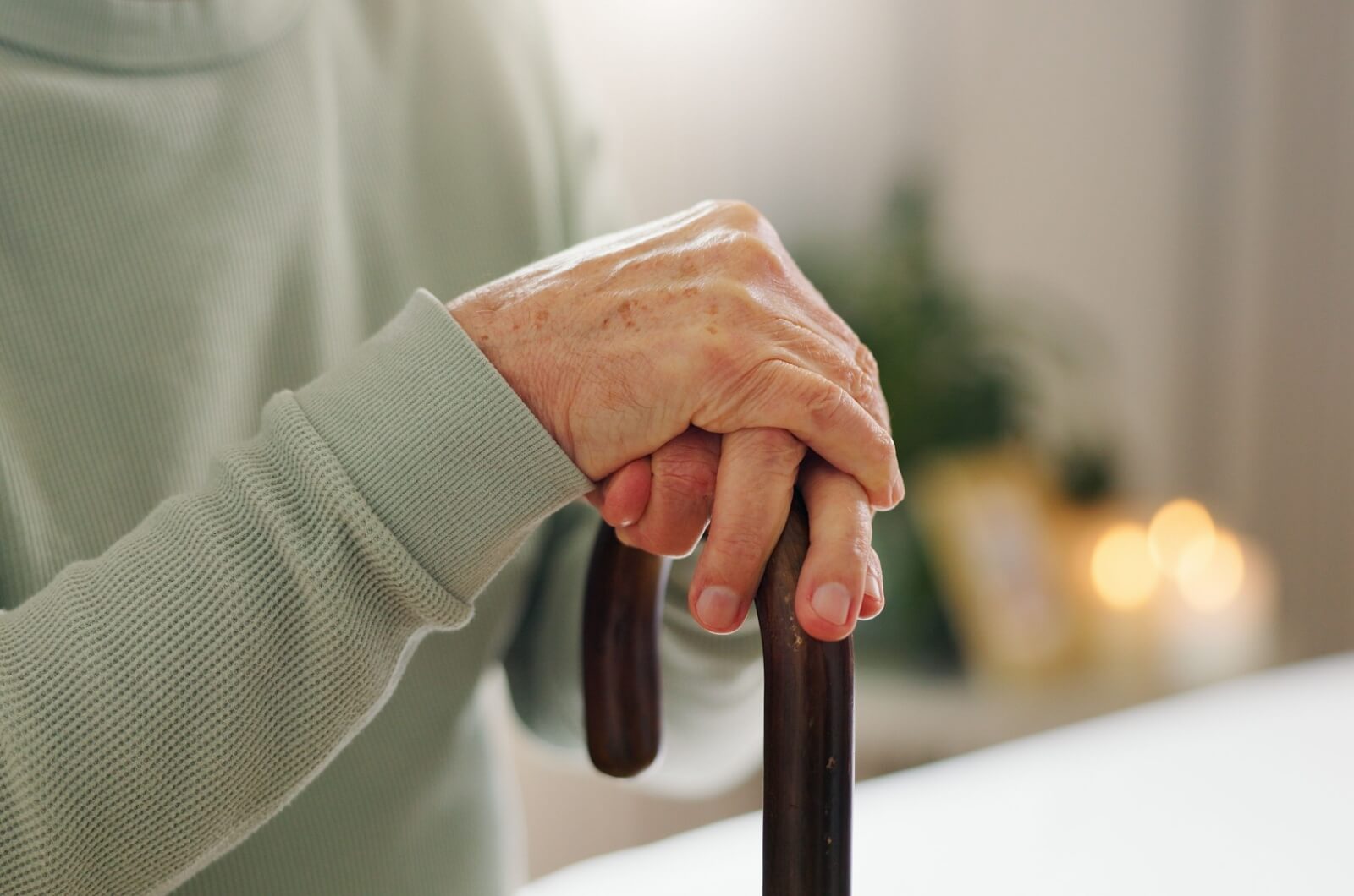 A close-up image of an older adult's hands on a walking cane.