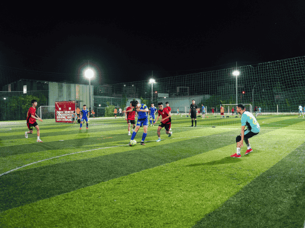 Youth playing soccer on artificial turf field at night, showing how infill supports turf performance in athletic settings.