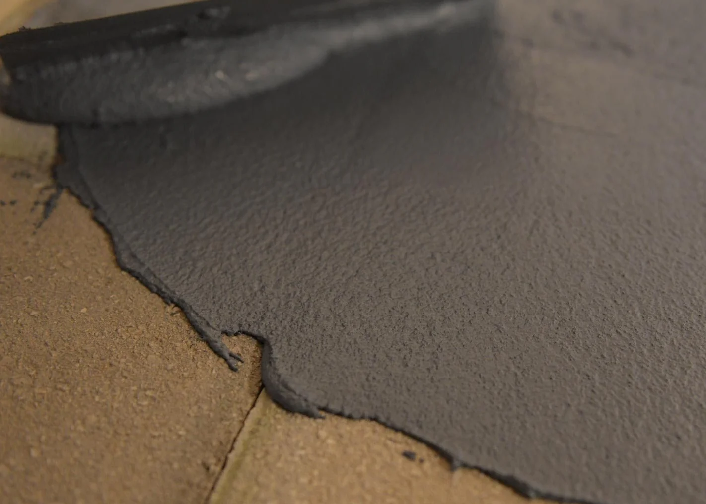 A close-up of gray-copied Acriflex Rapido being applied to bricks.