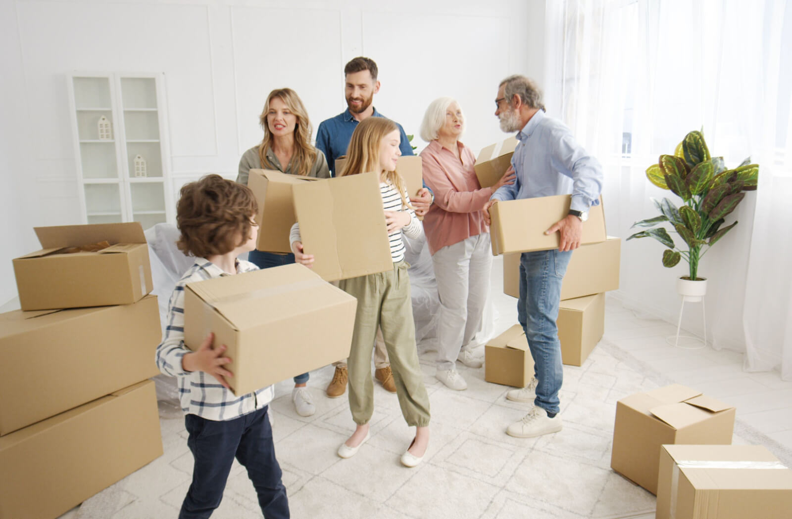 A multi-generational family working together to help their grandparents carry boxes during their move to a personal care community.