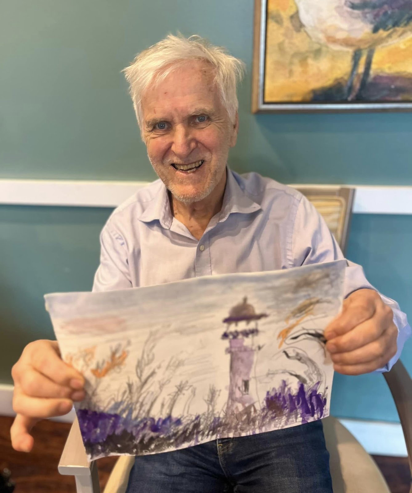 An elderly man in a memory  care unit holding up a picture he's drawn