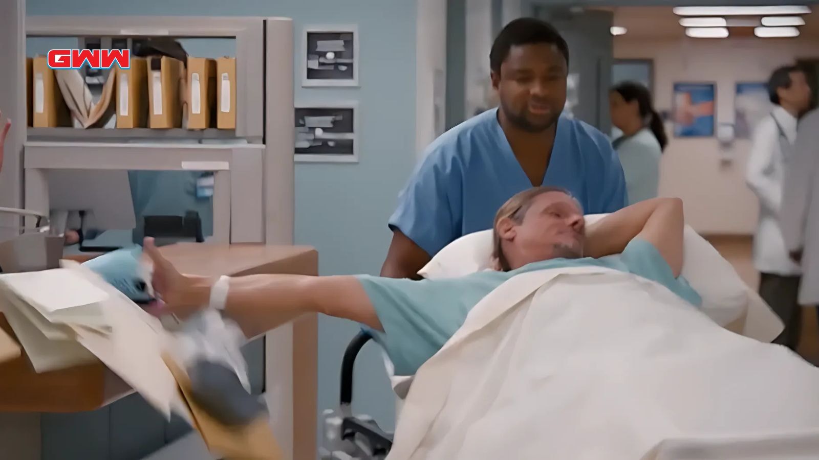 A mischievous patient on a stretcher intentionally knocks items off a desk