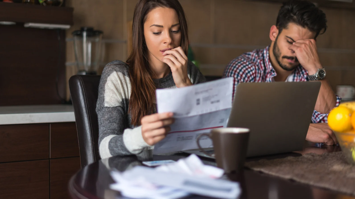 (Distressed couple reviewing documents at home, symbolizing the personal impact of civil rights violations such as unlawful fines, discrimination, or police misconduct.)