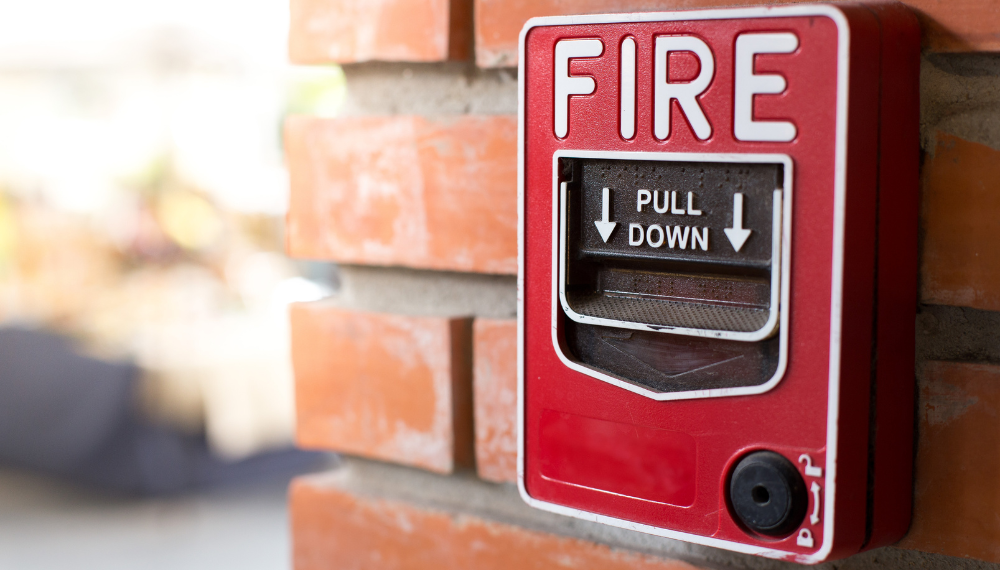 A red fire alarm on a brick wall

Description automatically generated