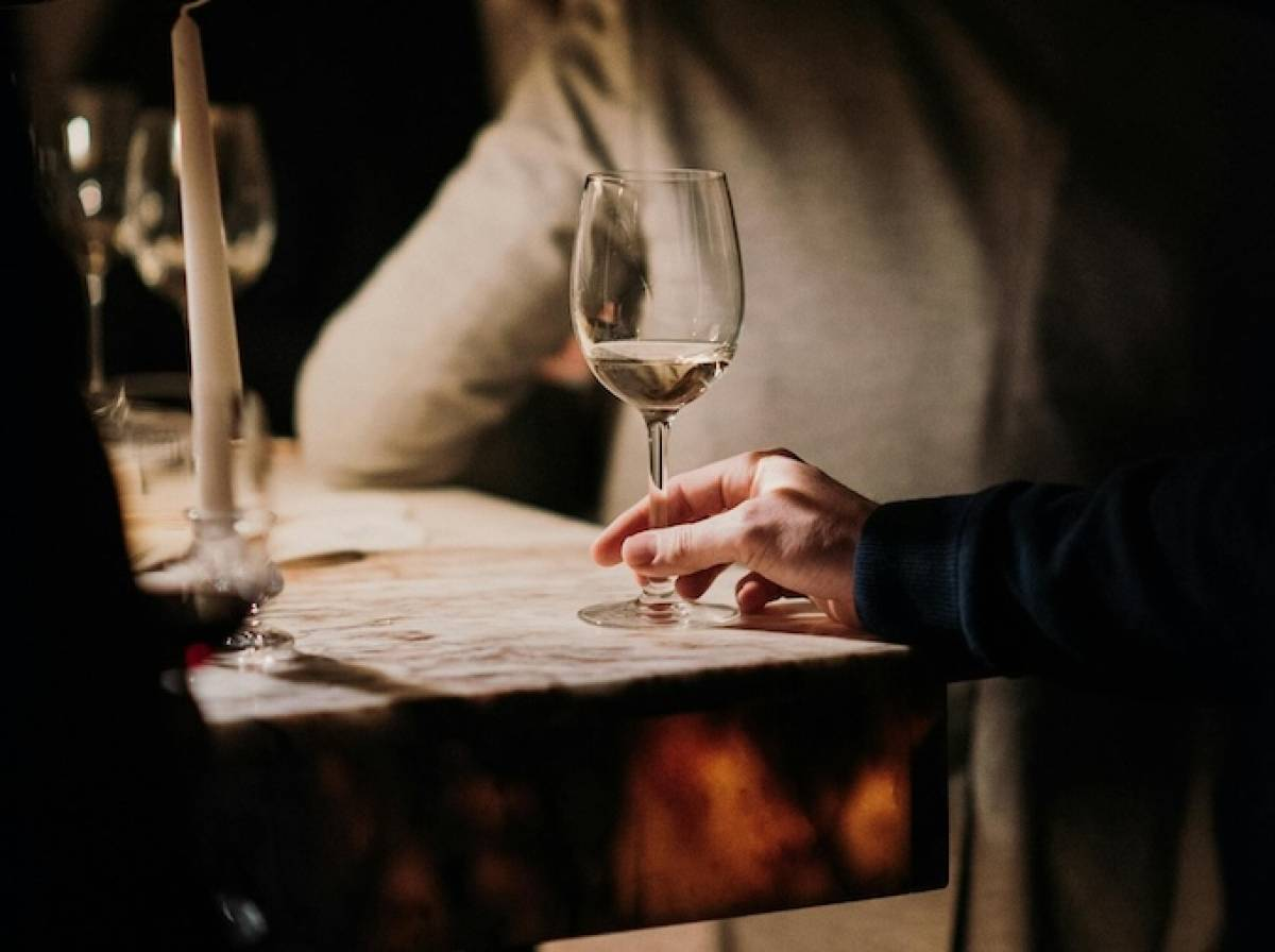 Someone holds a wine glass in a wine bar