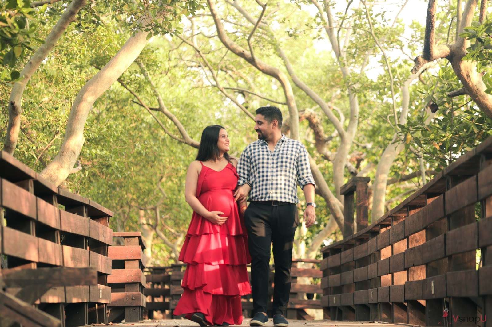 Pregnant couple on a bridge, gazing into each other's eyes for a romantic maternity photoshoot