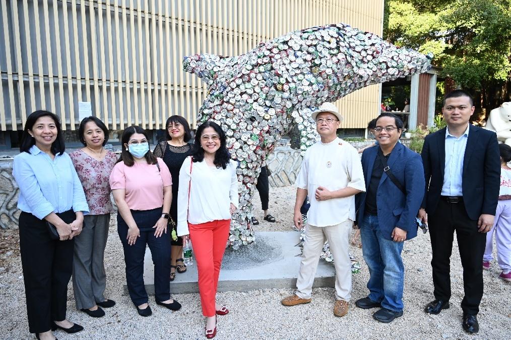 A group of people standing in front of a statue of a dolphinDescription automatically generated