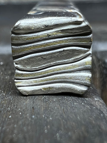 Close up of a mokume gane billet that has been fused together, many layers of metal stacked and pressed together to bond them.