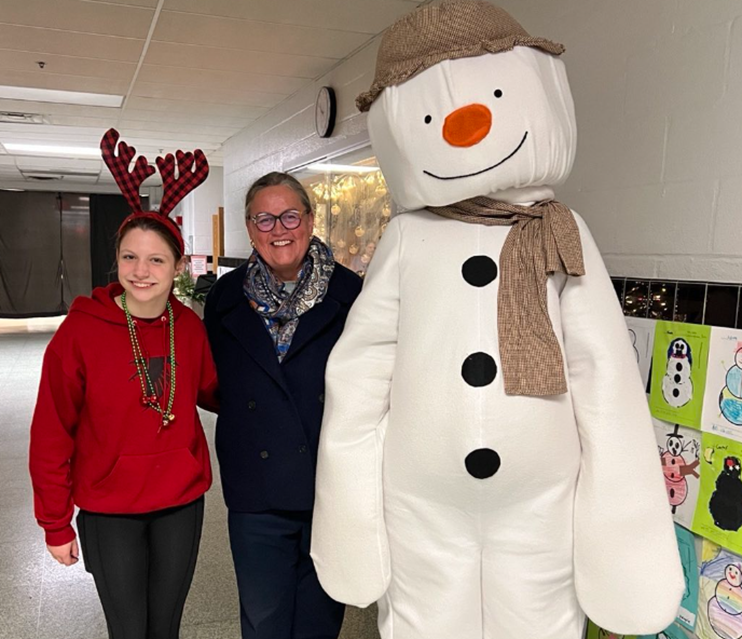 Dr. Reid with an elementary student and a person in a snowman costume. 