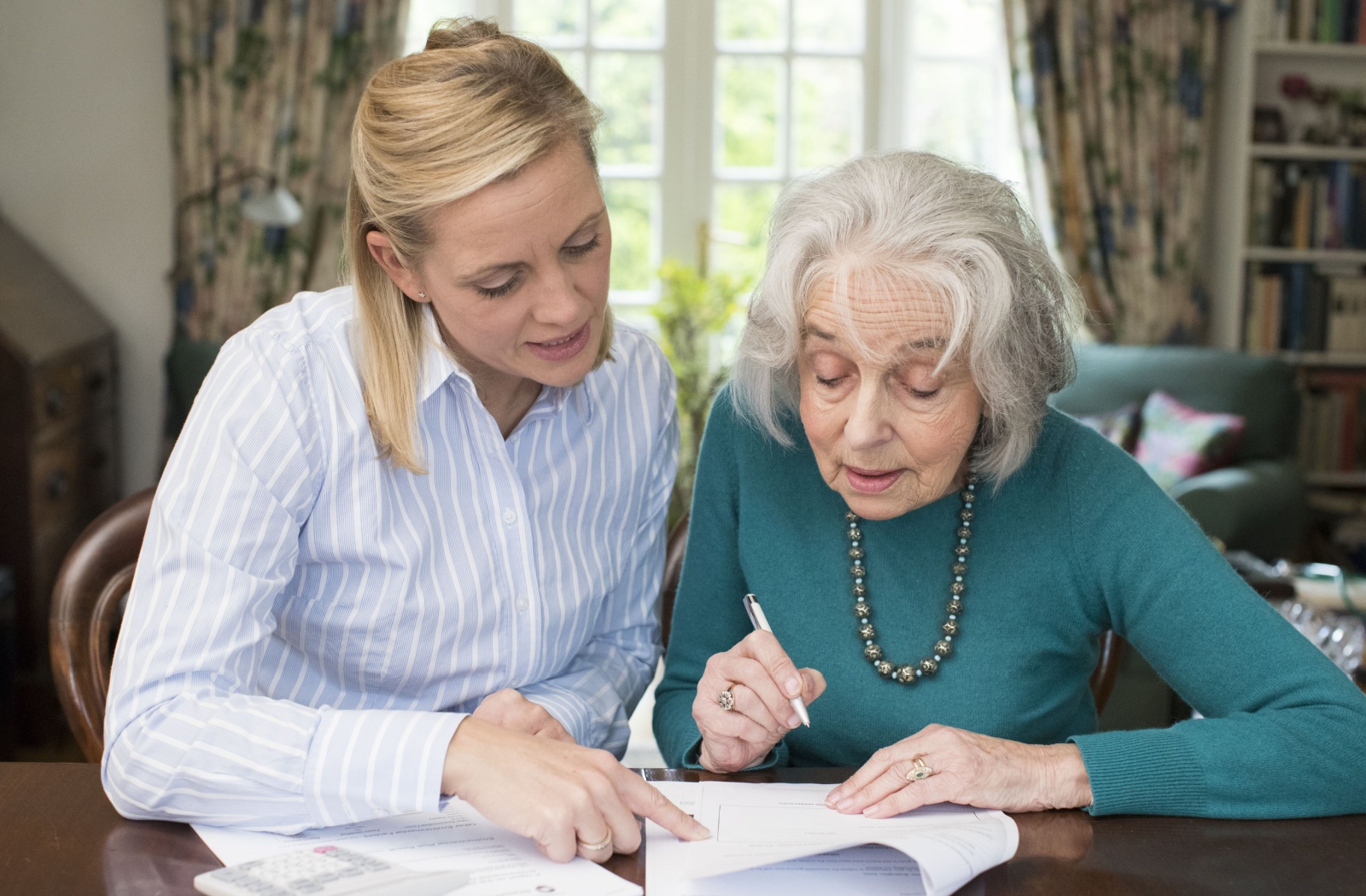 a young woman helps an older senior woman with paperwork
