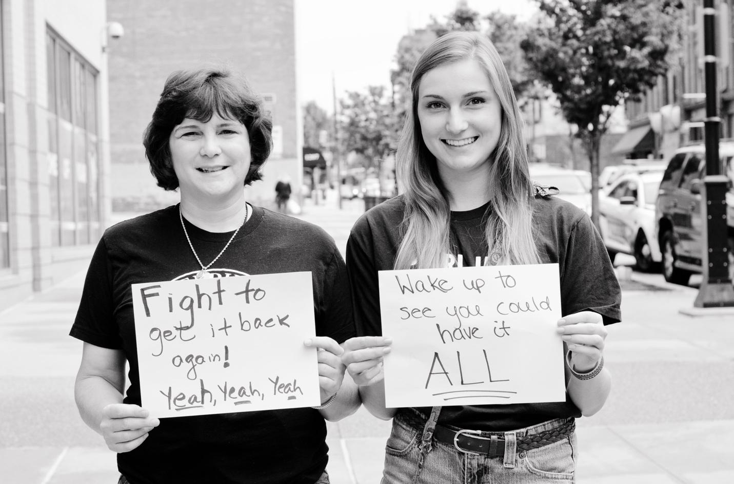 A couple of young women holding signsDescription automatically generated