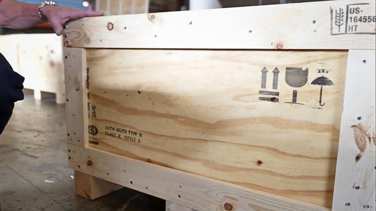 Close-up of a wood crate stamped with ASTM D6251, certifying its construction meets performance standards for shipping containers