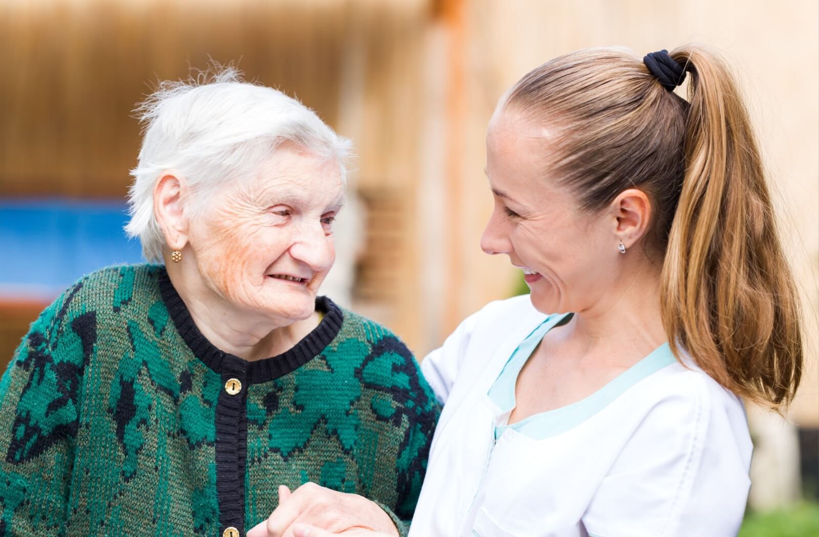 A smiling respite care staff having a conversation with a smiling senior resident