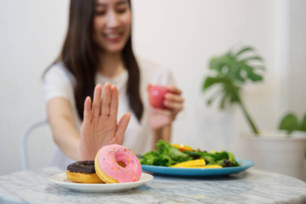 A woman smiling as she declines a donut, symbolizing her commitment to a healthy lifestyle after discontinuing HRT.