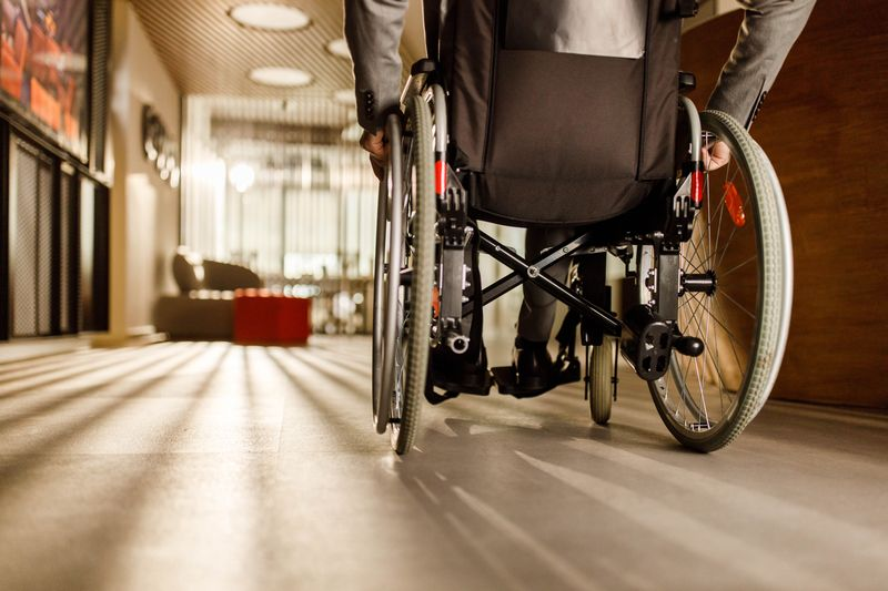 A patient with a hip injury wheels themselves down a hallway in a wheelchair. 