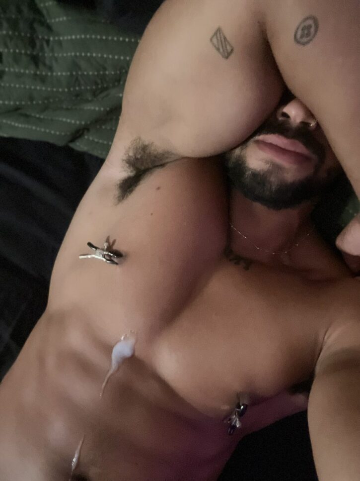 Lipe Scorpion wearing nipple clamps with his arm covering his face covered in cum all over his chest