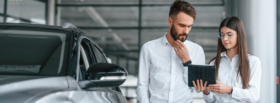 homem e mulher olhando o tablet ao lado do carro