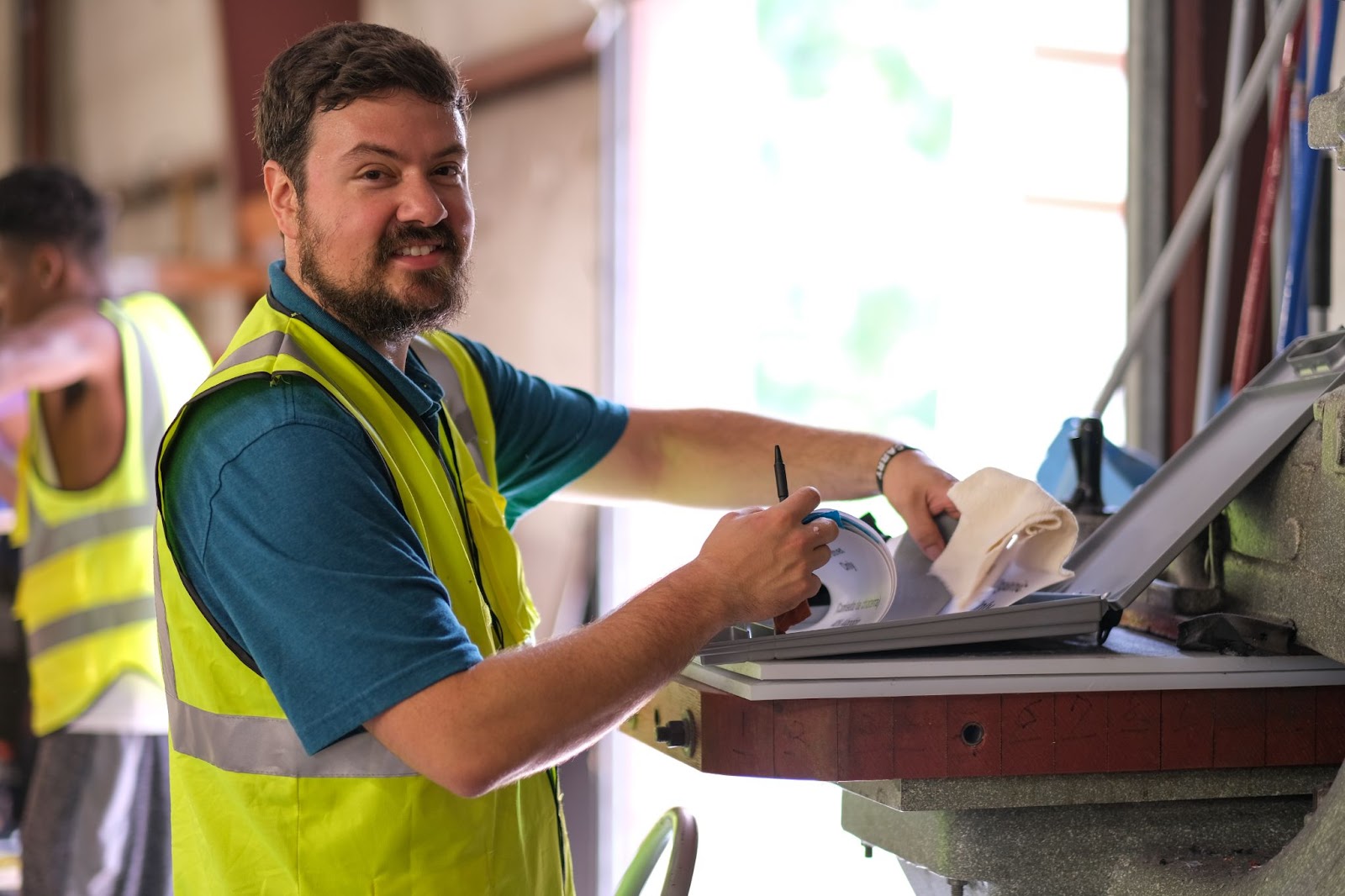 A handyman working in a workshop wearing a yellow vest