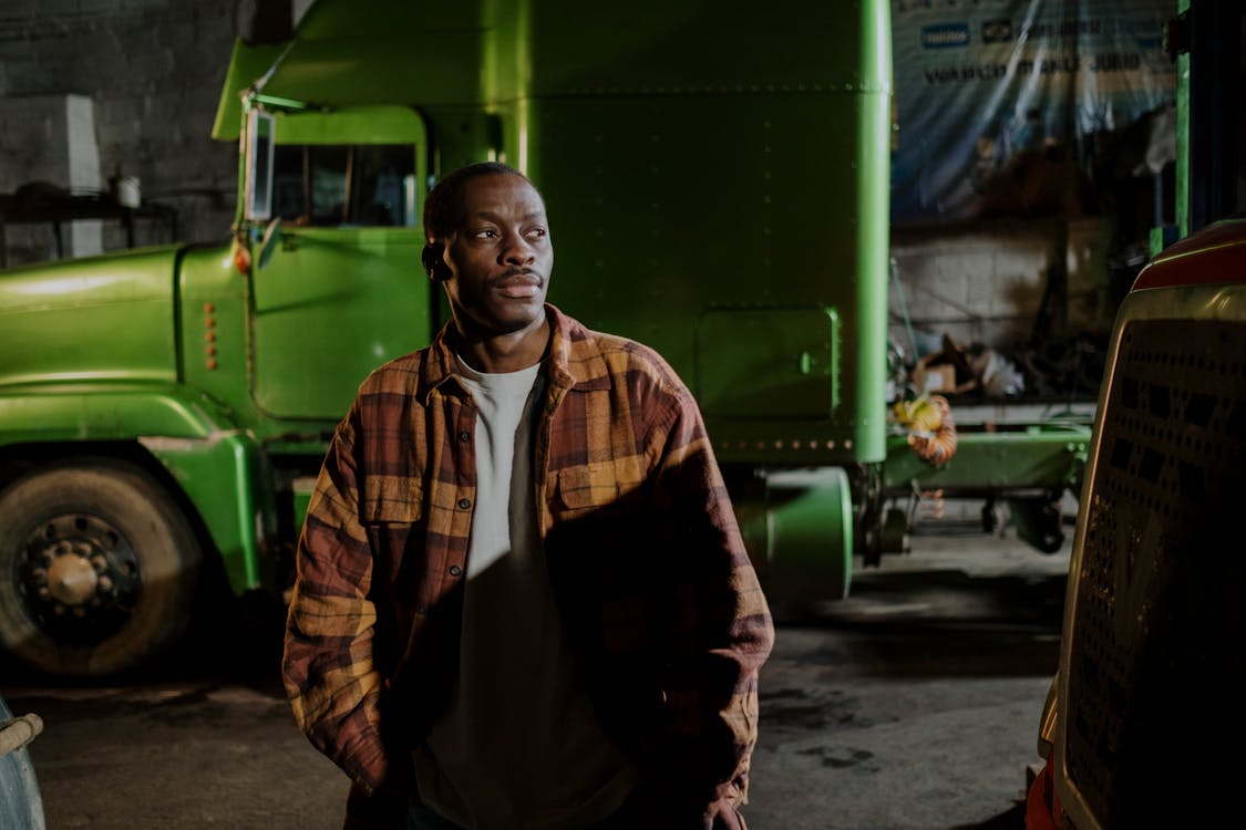 Free Man Standing Near the Green Truck Stock Photo