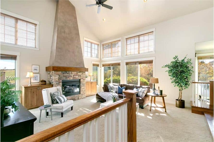 Living room with cozy seats, a stone fireplace, and plenty of windows that bring ample natural light in.