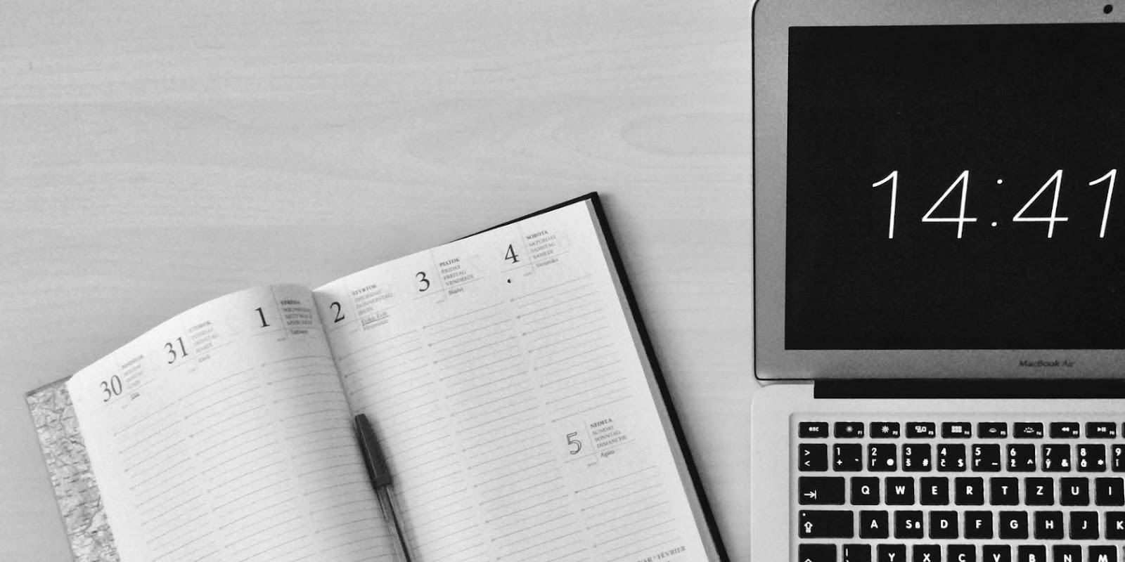 notebook and pen beside a laptop