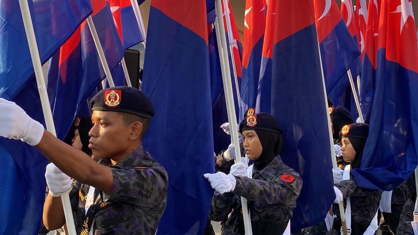 A group of people in uniform holding flags

Description automatically generated