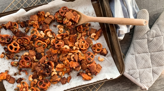 Un plateau de cuisson rempli de divers ingrédients de mélange montagnard, notamment des bretzels, des noix et des graines, fraîchement cuits et légèrement dorés.