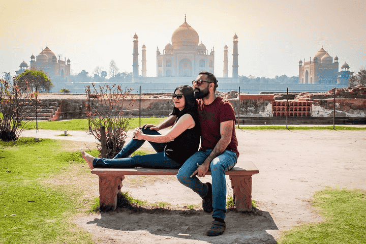 Pre-wedding photoshoot of a couple sitting in front of the Mehtab Bagh, wearing beautiful dresses and smiling gracefully.